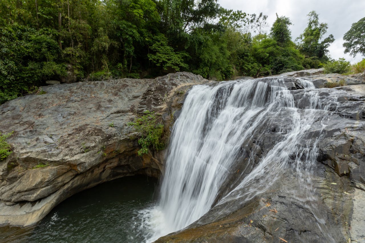 journey Stunning waterfall cascading over rocks in a lush green forest setting, capturing the essence of nature.